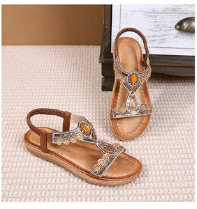 Détail de sandales bohèmes avec perles orange et bride en T ornée de strass argentés