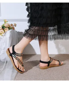 Close-up of Bohemian flat sandals featuring ethnic beadwork and a heart metal charm