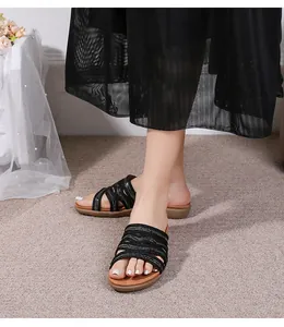 Lifestyle shot of black multi-strap flat sandals paired with an elegant black mesh skirt