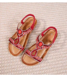 Détail de sandales plates bohèmes rouges avec embellissements en cristal et bride élastique