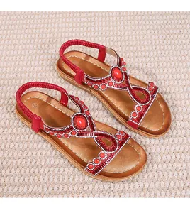 Détail de sandales bohèmes rouges avec strass, perles et bride de talon élastique