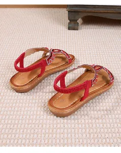 Détail de sandales bohèmes rouges avec broderies de perles et strass étincelants