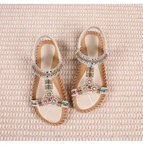 Detail van bohemien platte sandalen met strass bloemmotieven en een geweven zoolstructuur