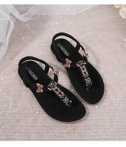 Detalle de sandalias negras planas de dedo con decoración de mariposa en strass brillante