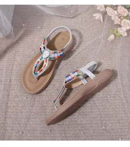 Detailed macro view of rhinestone T-strap flat sandals with colorful beaded accents
