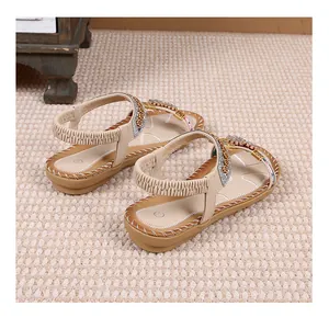 Detail van bohemien platte sandalen met strass, metalen ringen en stiksels op beige