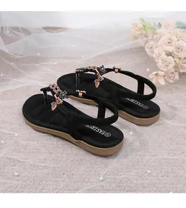 Detalle de sandalias negras con lazo de strass, tira elástica en el talón y suela cómoda