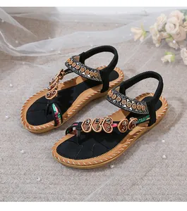 Detail of bohemian flat sandals featuring rhinestone heart patches and colorful woven straps