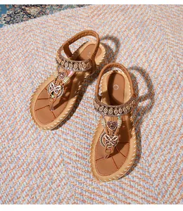 Detail of bohemian flat sandals featuring rhinestone heart charms and elastic strap