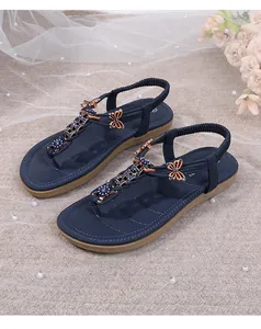 Detalle de sandalias azul marino con dije de mariposa dorada y adornos de pedrería