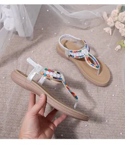Detail of bohemian flat sandals with colorful beads and silver glitter T-strap