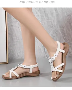 Détail de sandales bohèmes blanches avec fleurs en strass et bride en T sur le pied