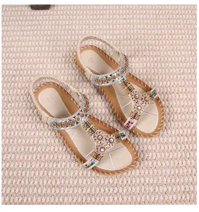 Detail van boheemse platte sandalen met bloemornamenten en sprankelende strass-accenten