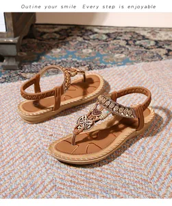 Detail of bohemian flat sandals with butterfly metal piece and beaded rhinestone T-strap