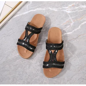Détail de sandales plates tressées noires avec paillettes argentées et semelle marron