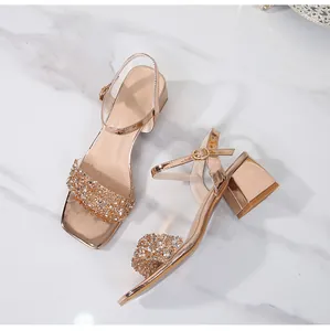 Macro detail of rose gold block heel sandals with rhinestone straps and ankle buckle