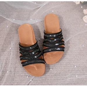 Detail shot of bohemian flat sandals featuring black wavy straps with sparkling sequins