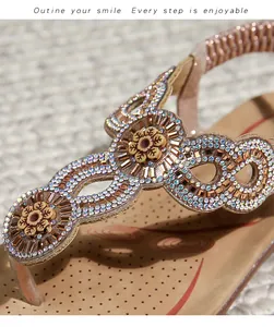Detail von flachen Bohemian-Sandalen mit funkelnden Strasssteinen und Blumen