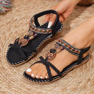 Λεπτομέρεια από μαύρα σανδάλια boho με χάντρες και σκαλιστά διακοσμητικά σε σχήμα καρδιάς