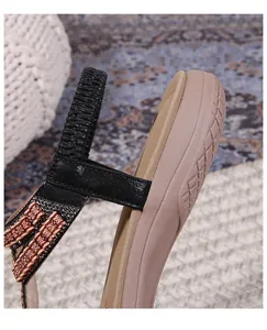 Detail of flat sandals featuring elastic heel straps and ethnic pattern woven band accents