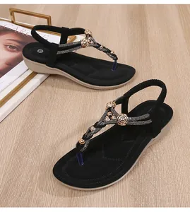 Λεπτομερής όψη μαύρων σανδαλιών με T-strap, χρυσές χάντρες και λαμπερά στρας