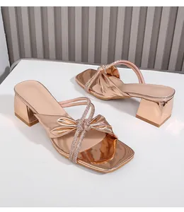 Detalle de sandalias de tacón ancho oro rosa con tiras adornadas con pedrería brillante