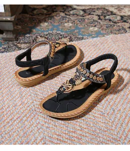 Detail of bohemian flat sandal with ethnic beadwork and butterfly design on black strap