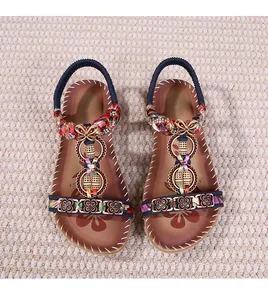 Dettaglio di sandali boho con cinturini colorati intrecciati e farfalla in metallo perlato