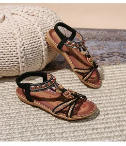 Dettaglio di sandali bohémien bassi con perline colorate e decoro in legno a farfalla