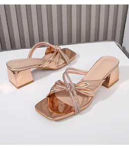 Detalle de sandalia oro rosa con lazo de pedrería y tacón de bloque resistente
