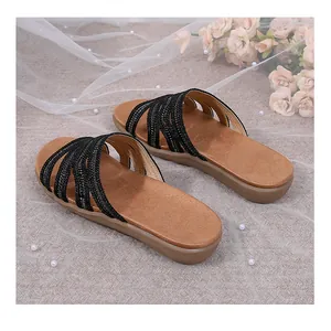 Top view of flat sandals featuring black sparkly rhinestone straps and tan soles