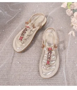 Detalle de sandalias oro champán con adornos de mariposa de bronce y cuentas de flores