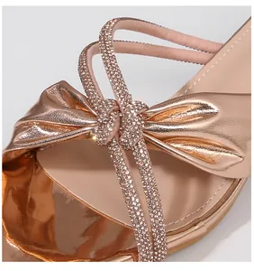 Detalle de sandalia de tacón oro rosa con diamantes de imitación y lazo en cuero sintético