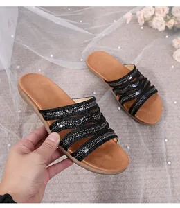 Detail of bohemian flat slide sandals with black sequins and brown padded footbed