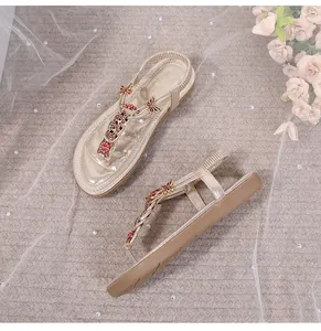 Detalle de sandalias doradas con mariposa de pedrería y correa elástica trasera para mujer