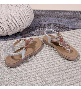 Close-up of Bohemian flat thong sandals with intricate beadwork and sequins on grass mat