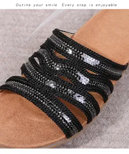Close-up of black braided straps with silver sequins and soft brown cushioned footbed