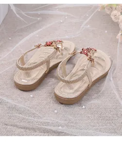 Detalle de sandalias planas bohemias con flores rojas y adornos de mariposas doradas