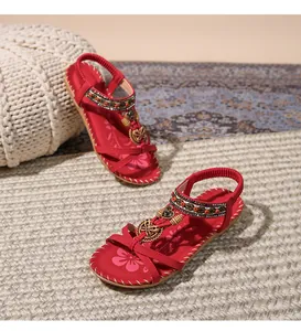 Dettaglio dei sandali boho rossi con cinturini di perline e accenti di farfalla