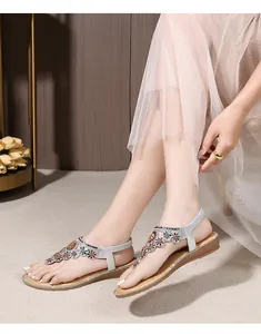 Detail of silver bohemian flat sandals featuring colorful rhinestone floral beadwork