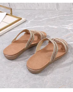 Détail de sandales plates pour femmes avec brides dorées tressées sur fond de marbre