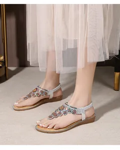 Detail of silver T-strap sandals with rhinestone floral accents and a comfy platform