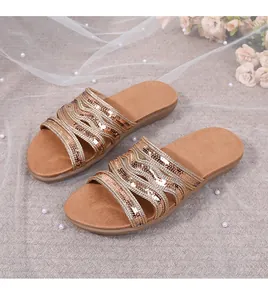 Close-up of golden hollow strap sandals with sparkling sequins and pearl accents