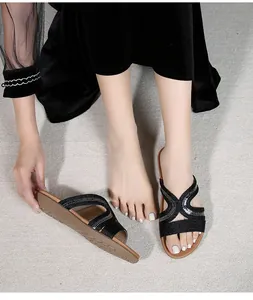 Detailed view of women's flat slide sandals with black sequined cross straps and embroidery