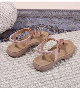 Detail view of pink rhinestone flat sandals with elastic backstrap and beaded embellishments