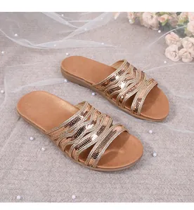 Detailed macro view of golden sequin wavy cross straps on casual flat sandals