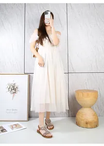 Dettaglio di un elegante abito bianco in rete con spalle scoperte e maniche a balze