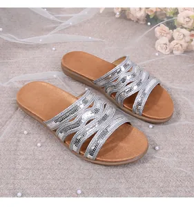 Close-up of bohemian silver sequin flat slide sandals with shiny woven straps and pearls