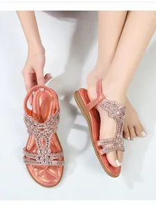 Λεπτομέρεια από σανδάλια boho με λαμπερά στρας σε λουλουδάτα σχέδια και λουράκι T