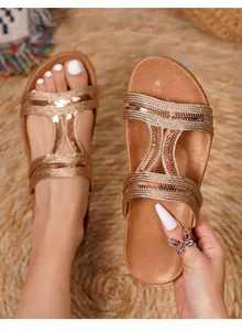 Macro shot of gold bohemian flat sandal featuring sparkling sequins and woven T-strap detail